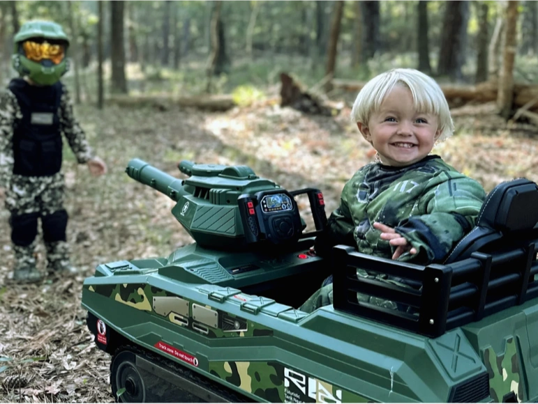 Kid Smiling looking at camera behind him while sitting on the M51 Shepard Tank by Tough Trucks for Kids