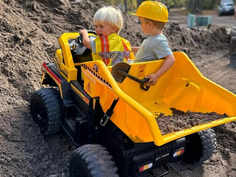 Two Kids riding up a dirt hill on the Big Kahuna Dump Truck by Tough Trucks For Kids