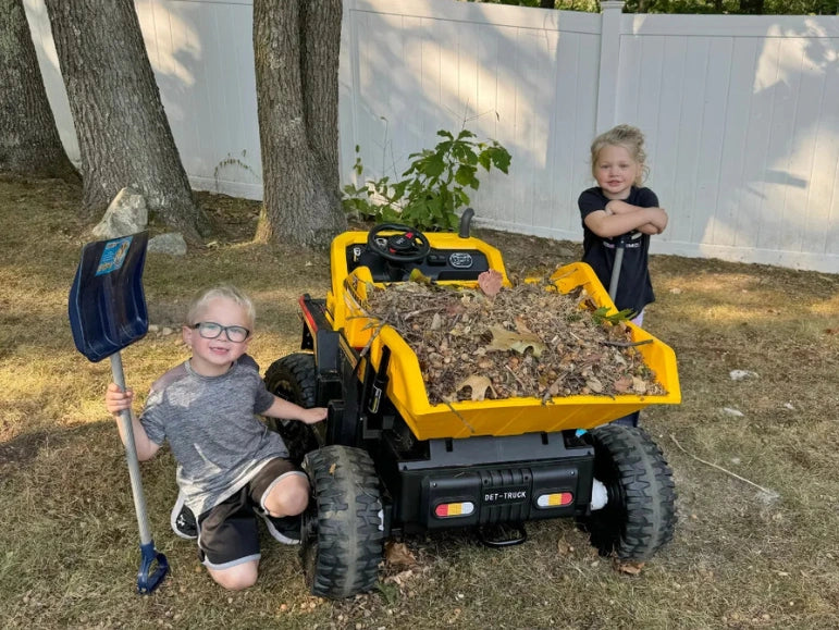 Brother and Sister looking at camera and smiling while hauling dried leaves at the back of the Big Kahuna Dump Truck by Tough Trucks For Kids